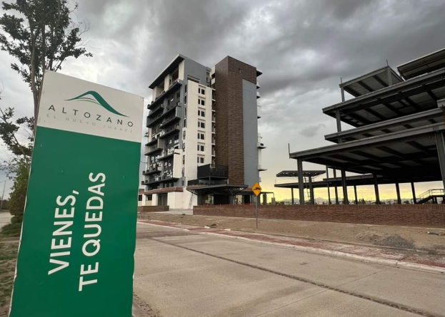 Acceso al desarrollo Altozano Ciudad Juárez con la torre de departamentos al fondo
